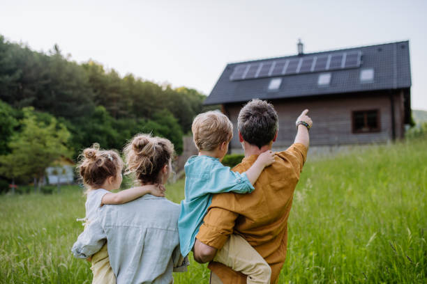 Happy family standing in front of their home with rooftop solar panels